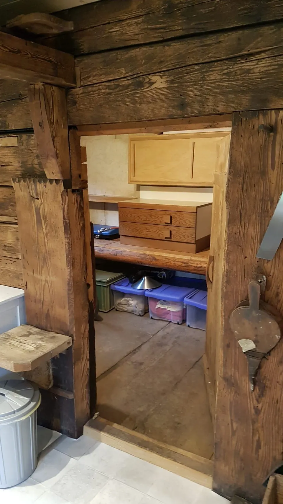 Blick durch eine alte Balkentür in den Vorratsraum mit Kisten und Kommode